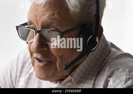 Face of old senior man in headphones speaking at mic Stock Photo