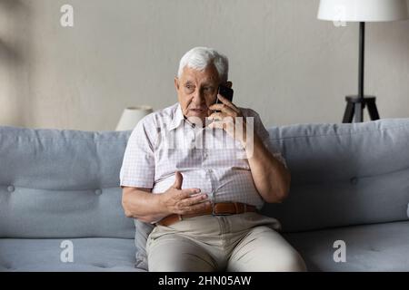 Worried concerned senior elder man talking on cellphone to doctor Stock Photo