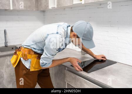 Installation of induction stove or cooktop by a master. Stock Photo