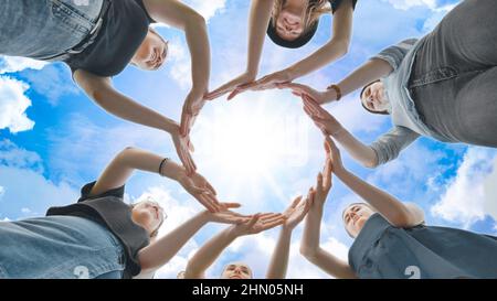 Friends make a circle with their palms against the blue sky. Stock Photo