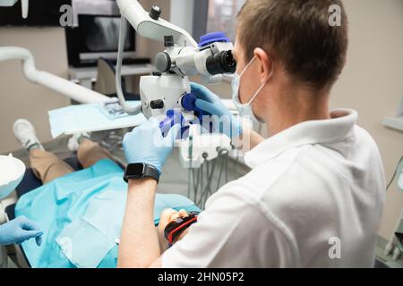 Dentist makes an operation using a dental microscope  Stock Photo
