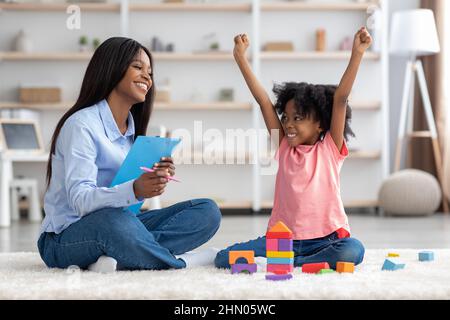 Emotional little girl raising hands up, having session with psychologist Stock Photo