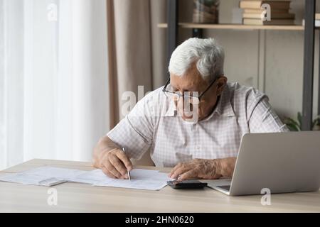 Elderly senior 80s man in glasses doing paperwork at home Stock Photo