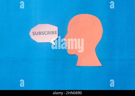 Paper Human face with Subscribe word on speech bubble isolated on blue background. Copy Space for text. Stock Photo