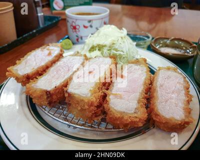 Tonkatsu, a Japanese breaded, deep-fried pork cutlet. Served with cabbage salad and wasabi. Stock Photo