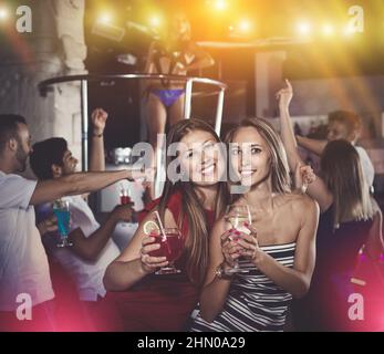 smiling women dancing in the night club with drinks in the hand Stock Photo
