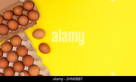 Organic fresh eggs in card boxes on vibrant yellow background. FLat lay Easter food composition Stock Photo