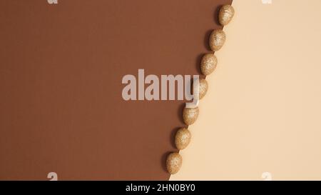 Pastel beige and brown background with golden glitter eggs for Easter. Flat lay concept Stock Photo