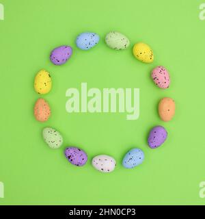 Easter circle frame with colorful rainbow eggs on bright green background. Flat lay minimal concept Stock Photo