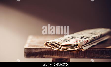 Good old newspaper on a wooden bench in the light of a floor lamp Stock Photo