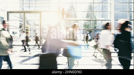 Crowd of anonymous men and women walking down an urban sidewalk with ...