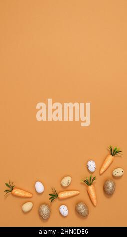 Vibrant orange background with Easter eggs and carrots arranged. Flat lay minimal concept Stock Photo