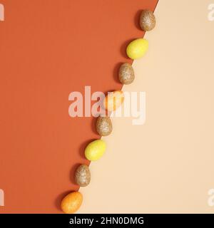 Easter arrangement with gold, yellow and orange eggs arranged in line on orange pastel beige background. Flat lay minimal. Stock Photo