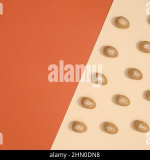Easter pattern with golden glitter eggs on orange pastel beige background. Flat lay minimal. Stock Photo