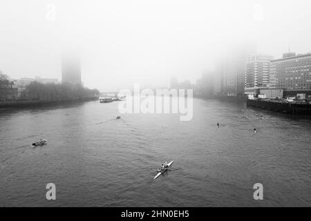 Rowers appear from under Vauxhall Bridge on a cold and misty London morning. London UK Stock Photo