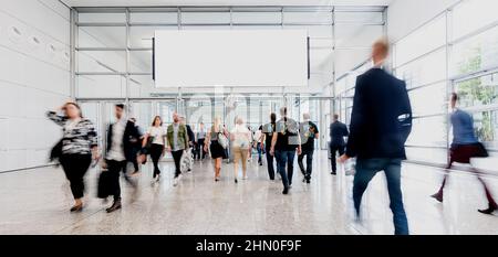 People on trade fair under a blank advertising poster or banner Stock Photo