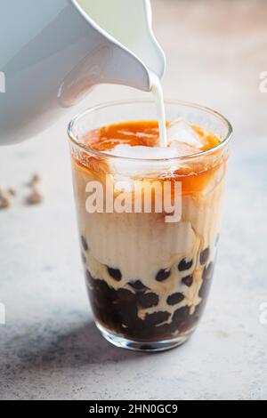 Cooking milk bubble tea with tapioca pearls in glass, gray background. Stock Photo