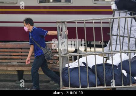 An employee at Hualamphong (Hua Lamphong) Station in Bangkok, Thailand, carting off used bedding from an overnight train Stock Photo