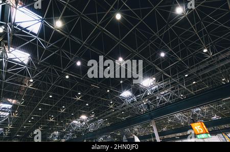 Lights and ventilation system in long line on ceiling of the dark office industrial building, exhibition Hall Ceiling construction Stock Photo