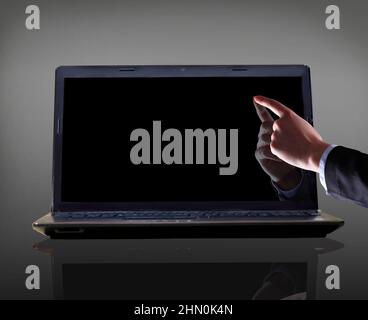 Close-up of male hand with forefinger pointing at laptop screen over black background Stock Photo