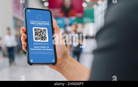 European Covid Pass Certificate of immunity against Covid19 on a mobile phone. Close up of woman holding a smartphone screen application certicy that Stock Photo