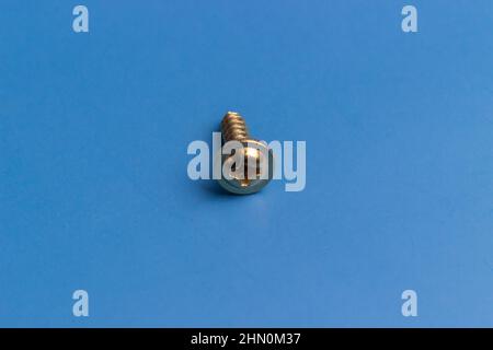 A lone screw isolated on a blue background, solitude Stock Photo