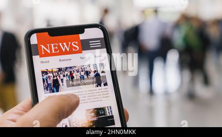 Online news in mobile phone. Close up of smartphone screen. Businessman reading articles in application. Hand holding smart device. Mockup website. Ne Stock Photo
