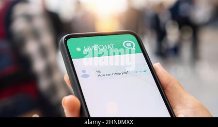 Businesperson use customer service and support live chat with chatbot and automatic messages or human servant outdoor. Assistance and help with mobile Stock Photo