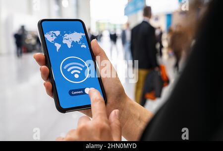 Woman hands holding phone with app vpn creation Internet protocols for protection private network on screen in a pedestrian zone. Stock Photo