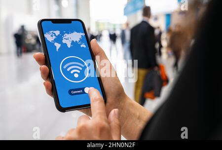 Woman hands holding phone with app vpn creation Internet protocols for protection private network on screen in a pedestrian zone. Stock Photo
