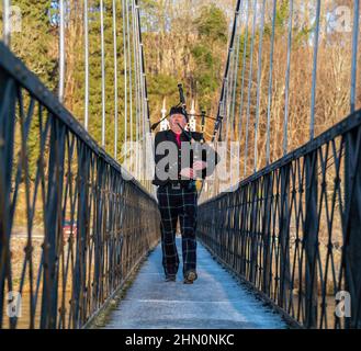 ABERLOUR,MORAY,SCOTLAND - 11 FEBRUARY 2022: This is a Piper walking over the Penny Bridge piping for the start of the Salmon Fishing on River Spey at Stock Photo