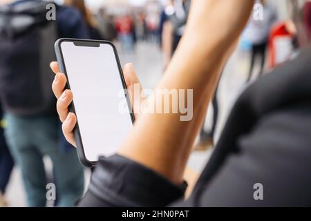 Businesswoman hand holding black cellphone with white screen at a trade fair, copyspace for your individual text. Stock Photo