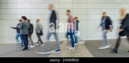 Anonymous blurred business people are walking around on a modern trade fair Stock Photo