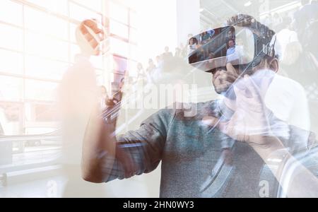 Bearded man wearing virtual reality goggles in modern business center. Gaming with with VR headset. Stock Photo