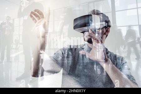Attractive young man wearing virtual reality goggles/VR headset on a gaming exibition Stock Photo