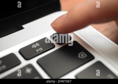 Kharkov, Ukraine - February 9, 2022: Hand pressing fingerprint scanner key on modern laptop keyboard. Finger print button closeup Stock Photo