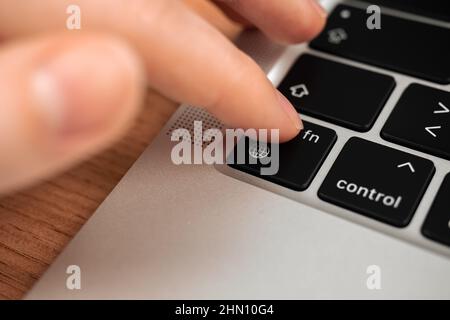 Hand pressing the globe key on modern laptop keyboard. The globe sign and symbol closeup Stock Photo