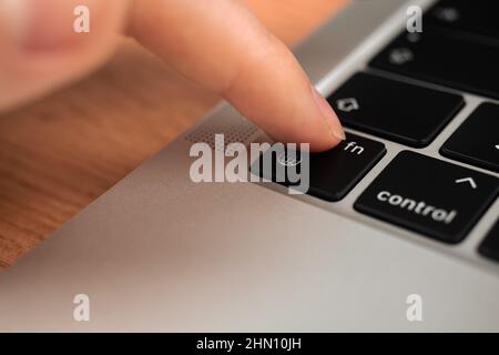 Hand pressing the globe key on modern laptop keyboard. The globe sign and symbol closeup Stock Photo