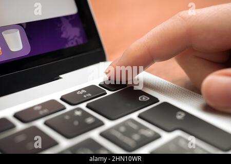 Kharkov, Ukraine - February 9, 2022: Hand pressing fingerprint scanner key on modern laptop keyboard. Finger print button closeup Stock Photo