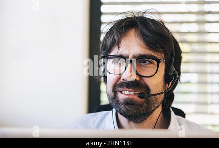 Smiling friendly handsome male call centre operator work in a office Stock Photo