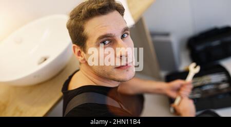 Handyman at work. Plumber Repairing Sink with wrench In Bathroom Stock Photo