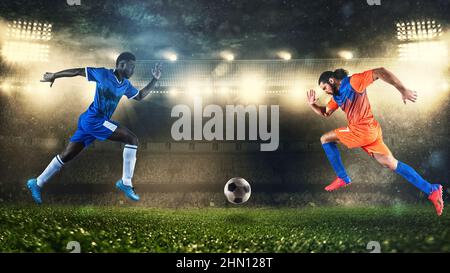 Two soccer players challenge each other chasing the ball at the stadium Stock Photo