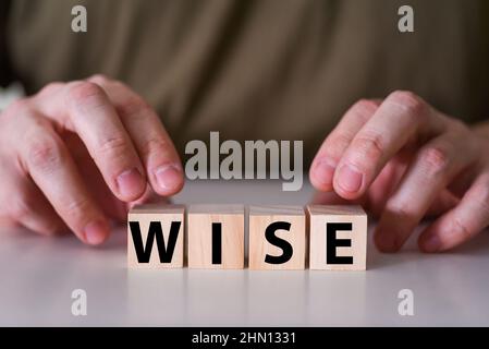 A conceptual image with the word Wisdom on wooden blocks or cubes held by human hands. A wise man. Stock Photo