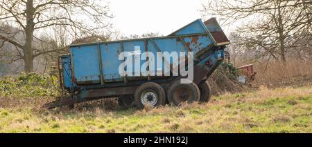 A pair of blue old and rusty trailers parked in an agricultural field in rural Norfolk Stock Photo