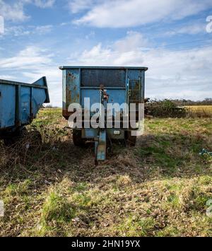 A pair of blue old and rusty trailers parked in an agricultural field in rural Norfolk Stock Photo