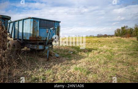 A pair of blue old and rusty trailers parked in an agricultural field in rural Norfolk Stock Photo