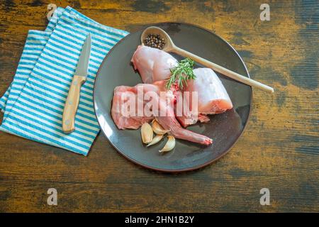 raw rabbit in a plate on a wooden table Stock Photo