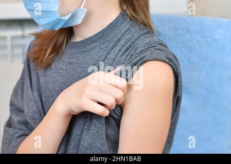 Young girl wearing blue protective mask getting ready to be vaccinated. Covid-19 vaccination campaign. Stock Photo