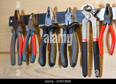 various sorts of pliers hanging on magnet hanger Stock Photo