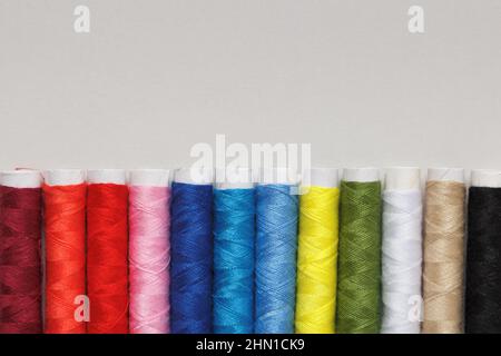 Multicolored threads in a row on a gray background with copy space. Stock Photo